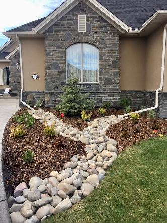 Dry river bed landscape construction in Calgary front yard for drainage