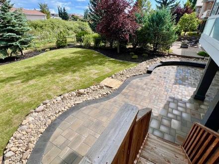 Large paving stone patio with river rock border construction in Calgary yard