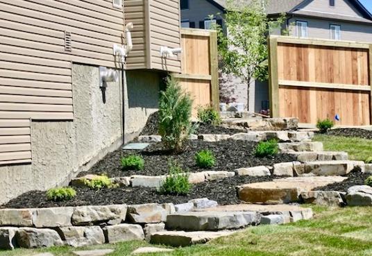 Tiered natural rock garden beds construction in Calgary acreage